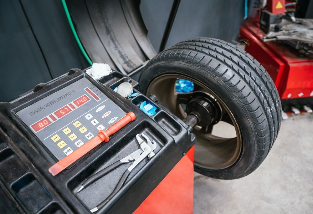 Tire balancing machine with a car wheel mounted and a control panel in a garage