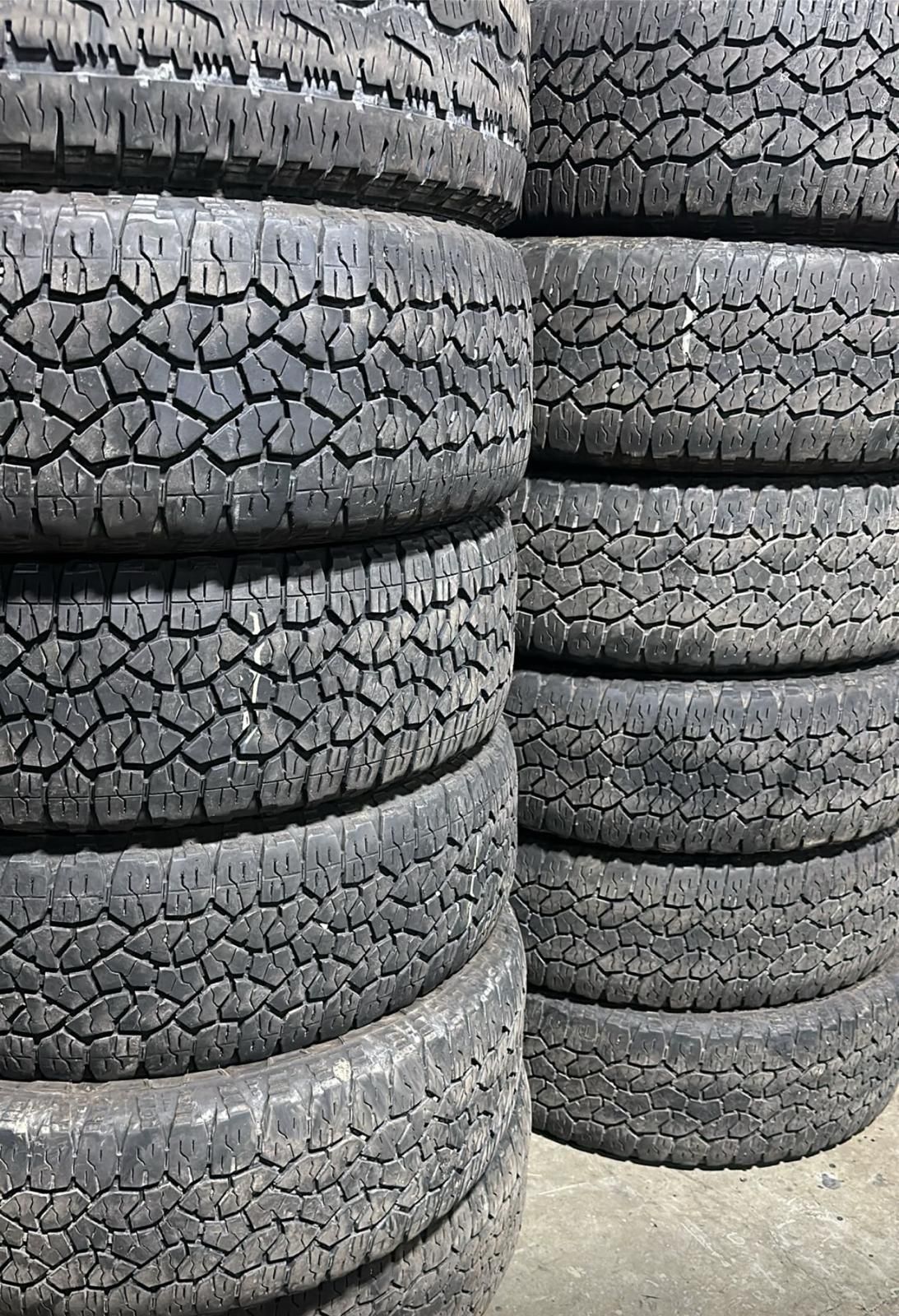 Stacked black off-road tires piled in a warehouse or storage area.