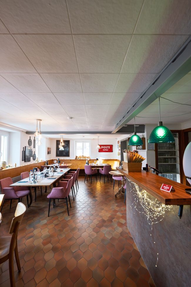 Salle à manger avec une longue table dressée pour un repas, chaises roses, fleurs, bougies et planches à découper décoratives.