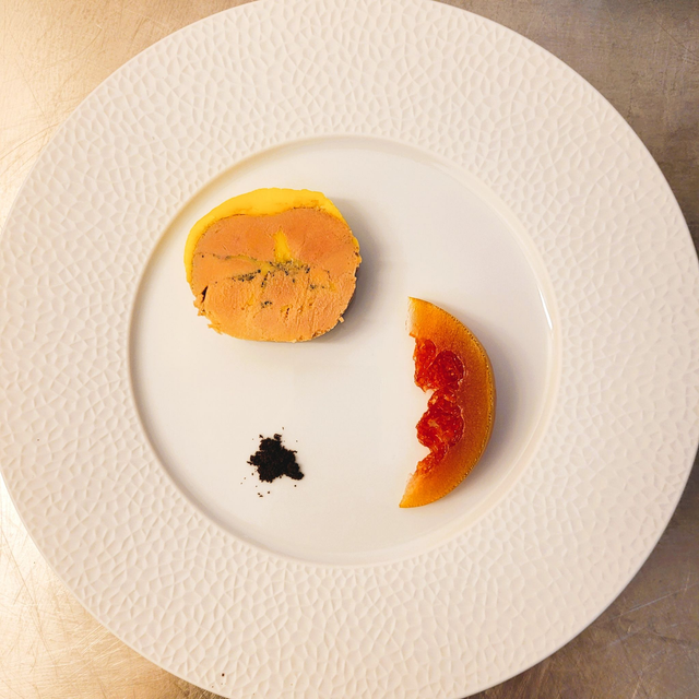 Assiette ronde avec des aliments orange et jaunes, et une pointe de sauce noire.