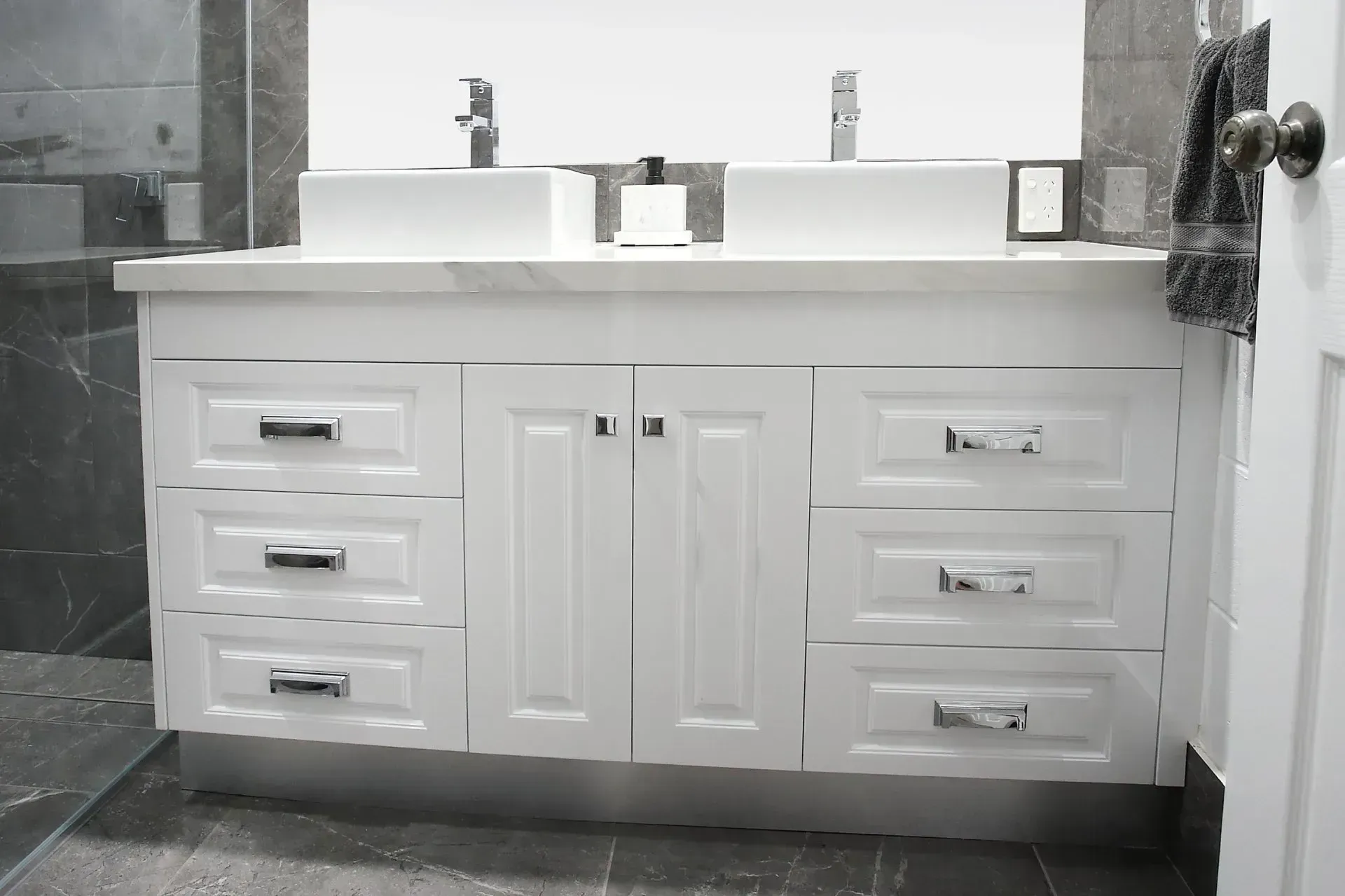 White Bathroom Vanity With Two Sinks, Chrome Hardware, And Gray Tiled Floor And Wall — B & C Cabinets in Mareeba, QLD