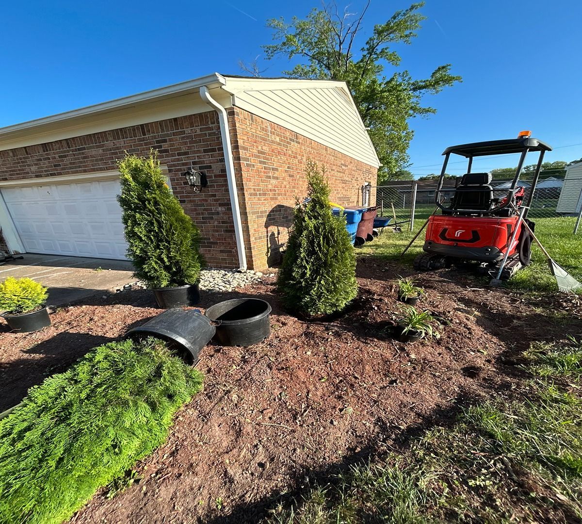 Brick house landscaping with shrubs, mulch, and a red utility vehicle in the yard