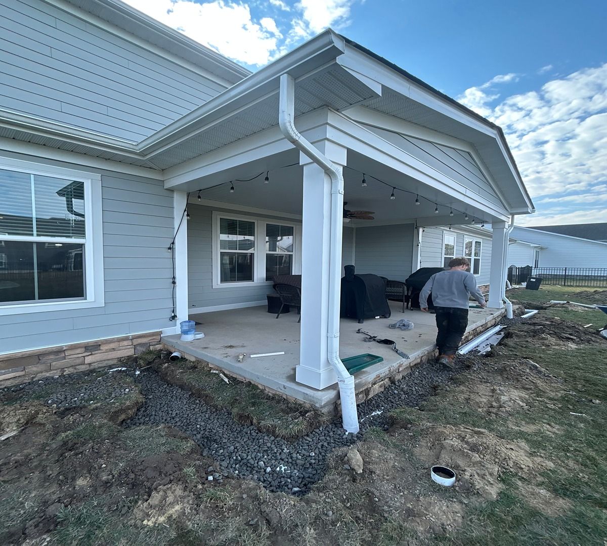 Front porch under construction on a white house, with workers and unfinished ground around it