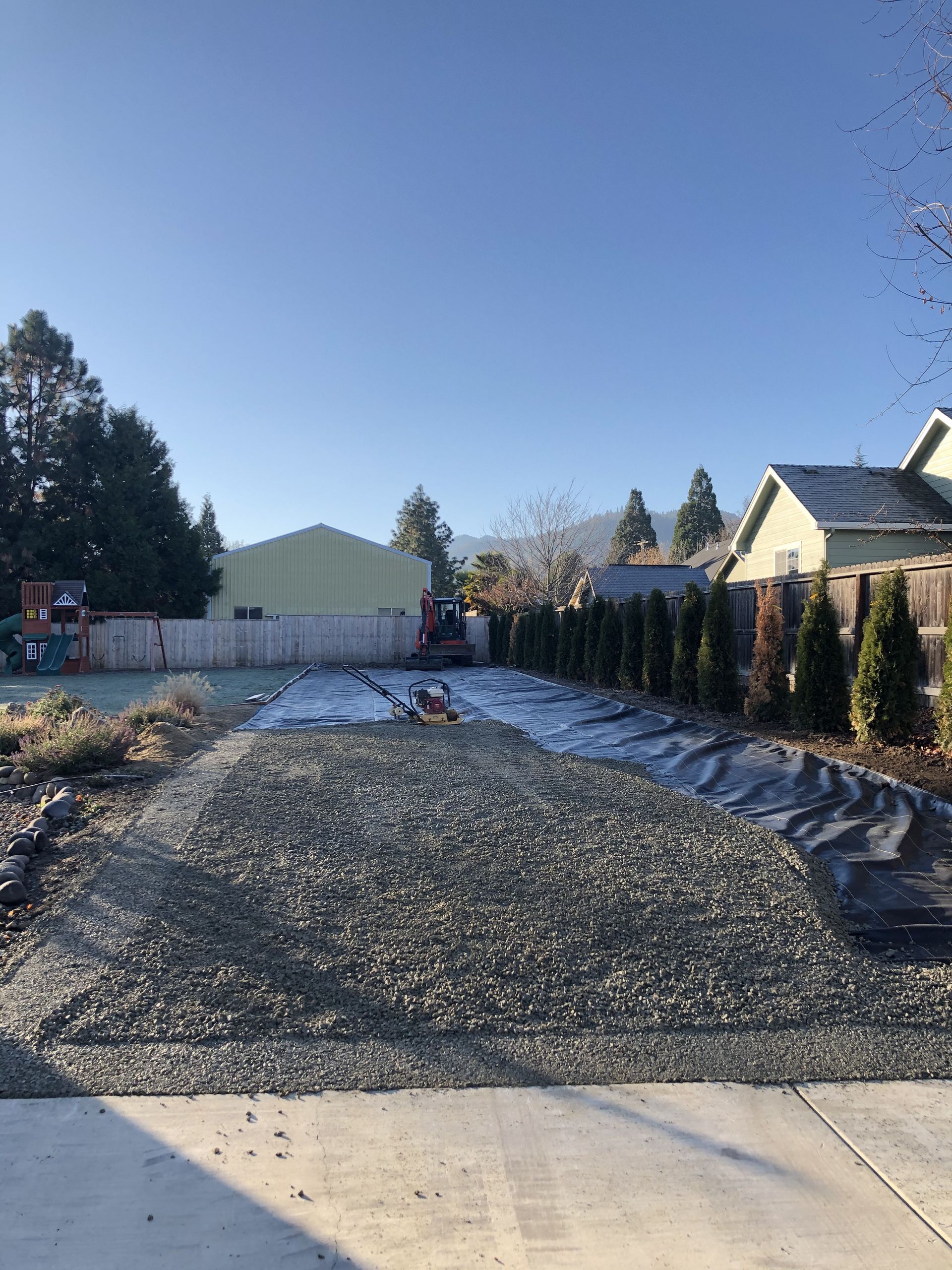 A gravel driveway is being built in front of a house.