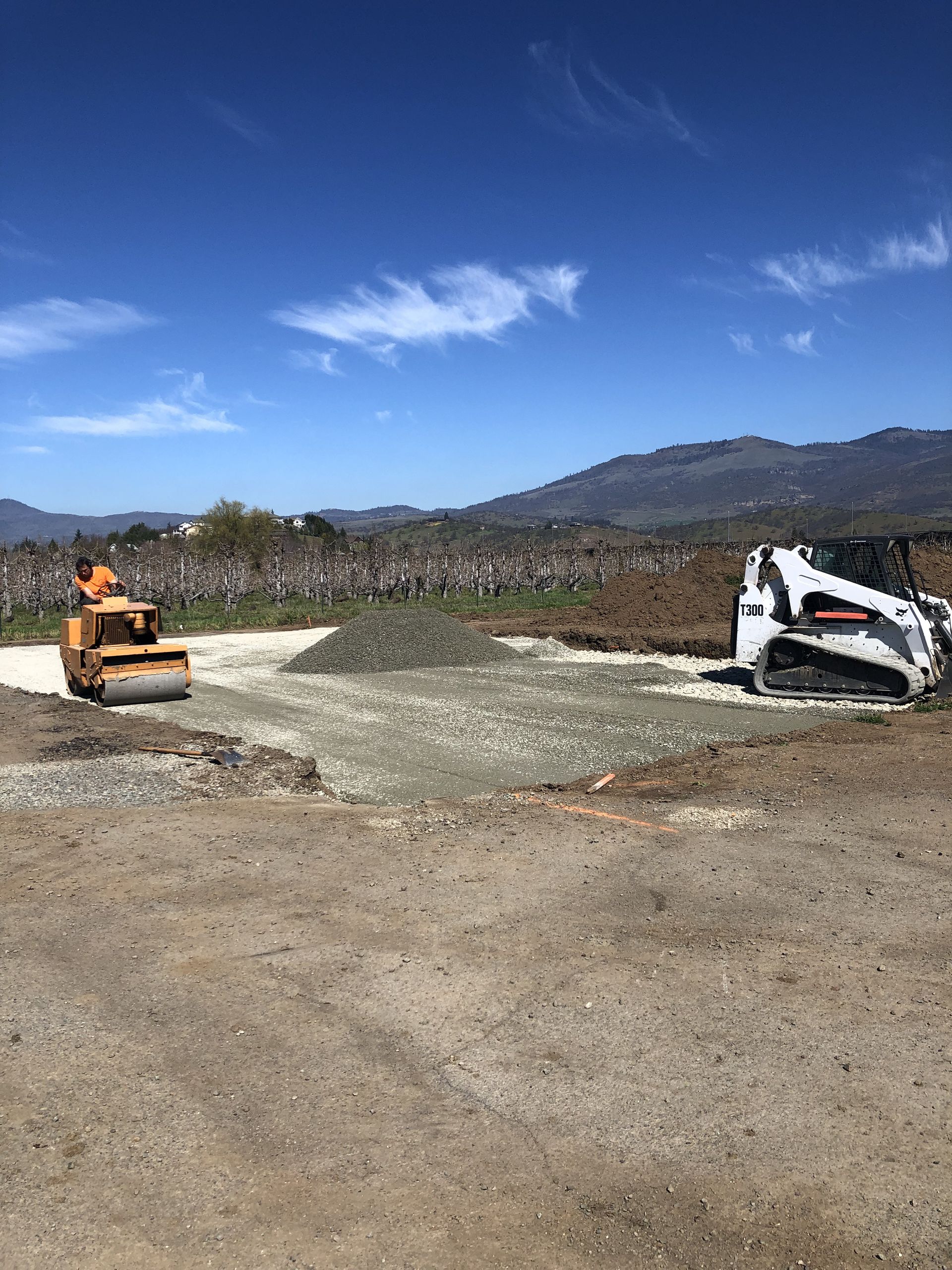 A bulldozer and a compactor are working on a dirt road.