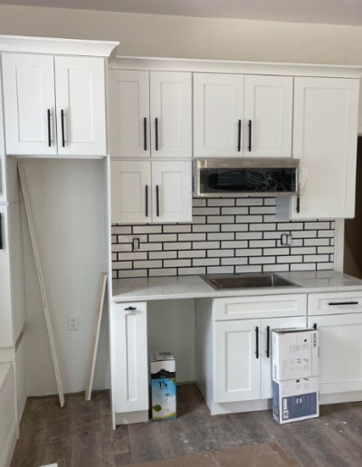 A kitchen with white cabinets and a brick wall