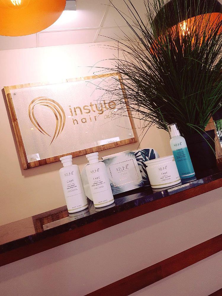 A Bottle of Lotion is Sitting on a Counter Next to a Plant — Instyle Hair on B in Berserker, QLD