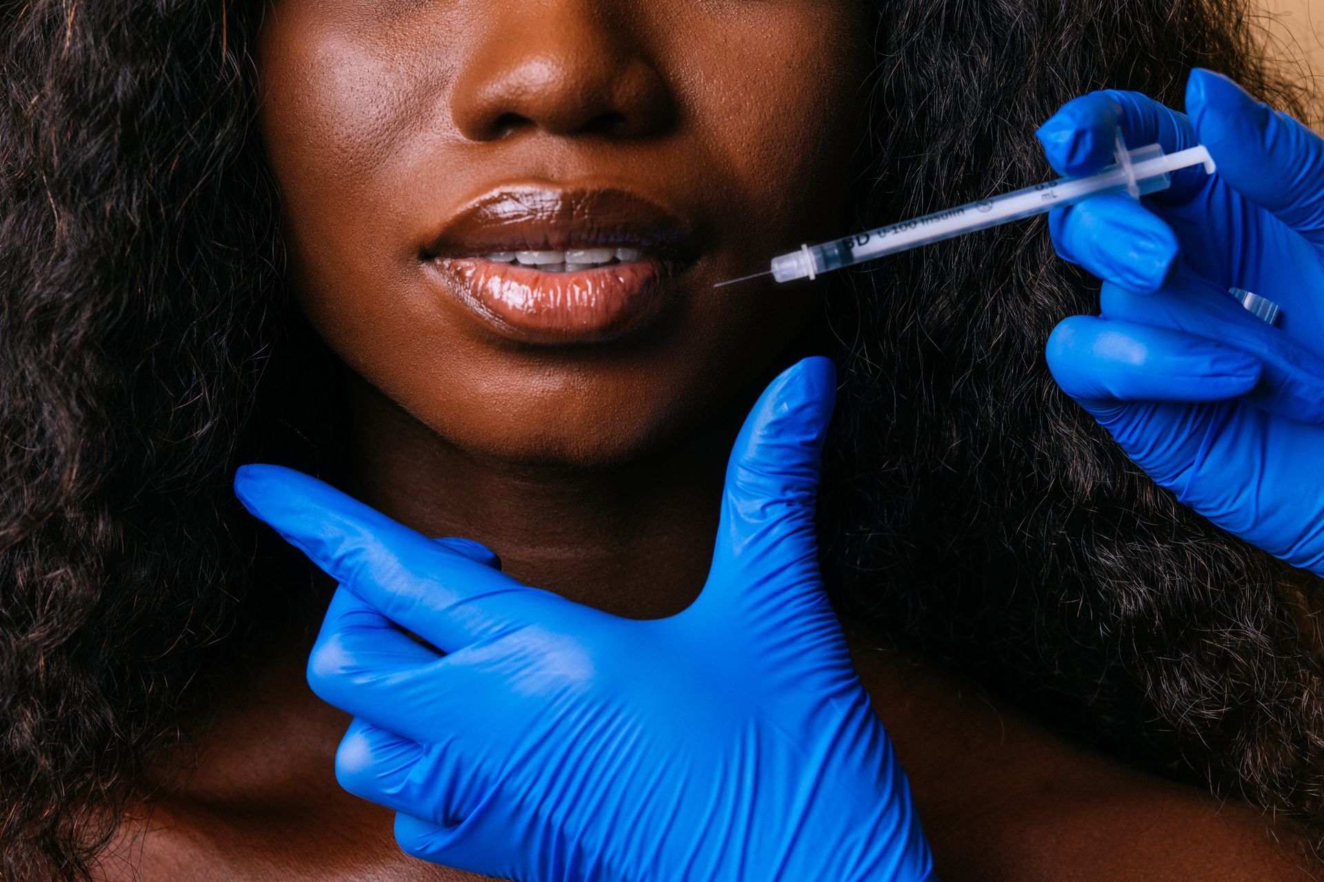 A woman is getting a botox injection in her lips.