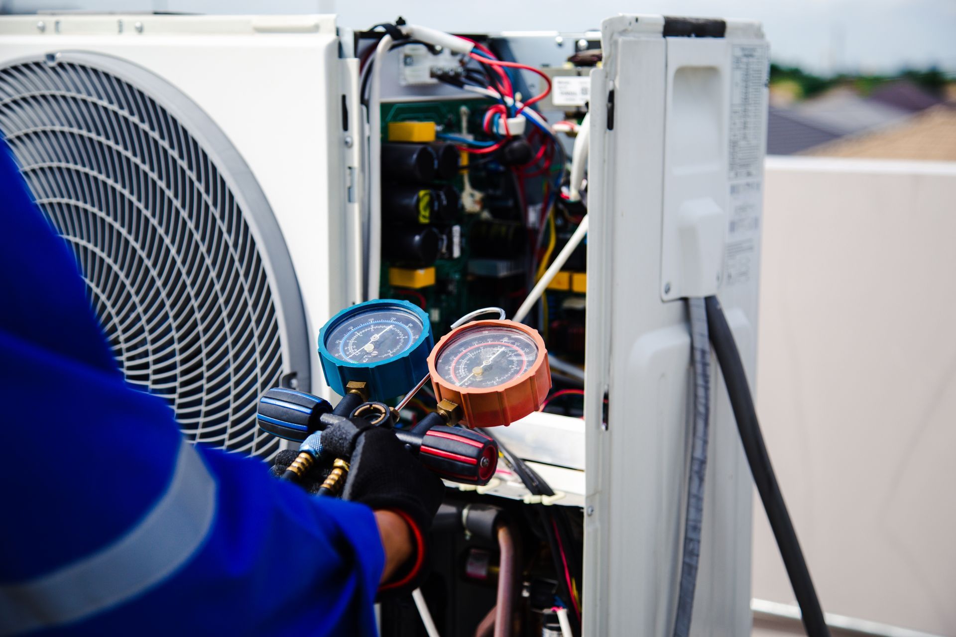 Technician servicing HVAC unit with gauges and tools outdoors