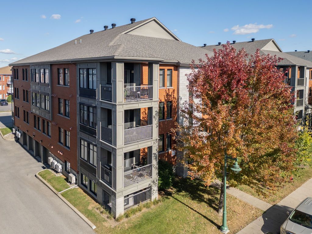 Immeuble d'appartements moderne en briques avec balcons donnant sur une rue bordée d'arbres par une journée ensoleillée