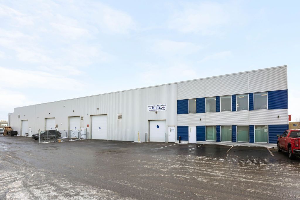 Snowy industrial warehouse exterior with white siding and blue accents