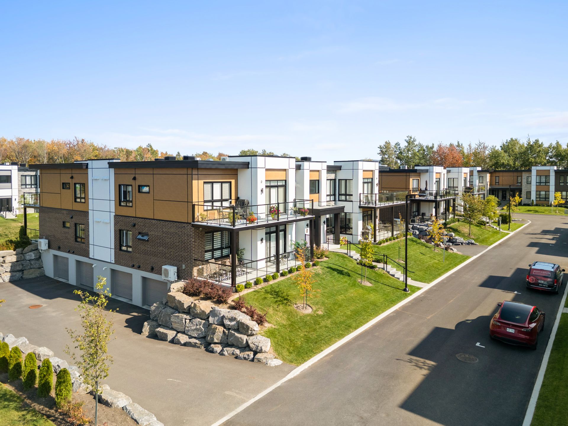Row of modern brick townhouses with black trim, front porches, and a quiet residential street