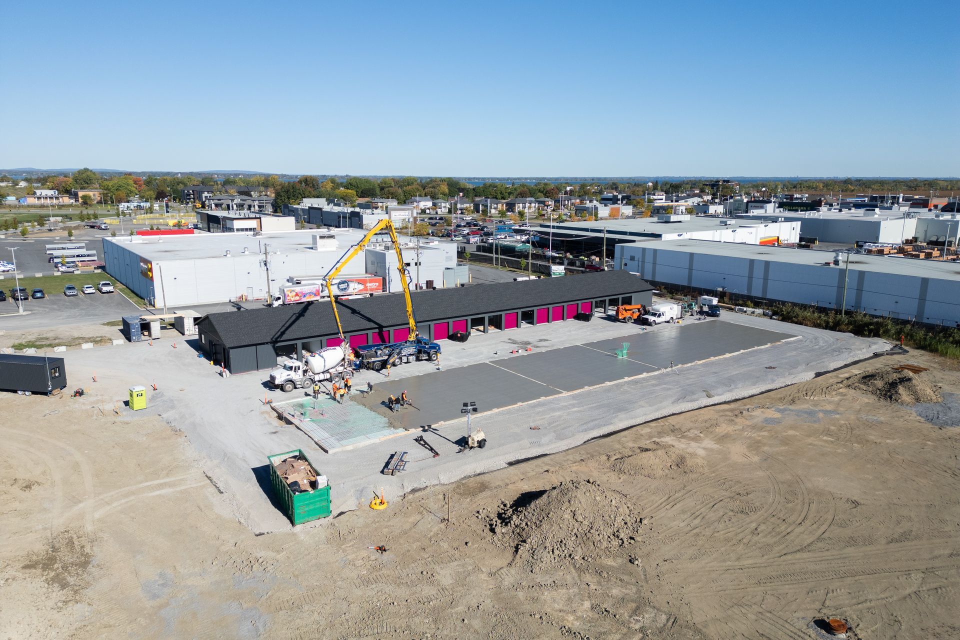 Aerial view of a construction site with concrete slab, pink equipment, and surrounding dirt lot
