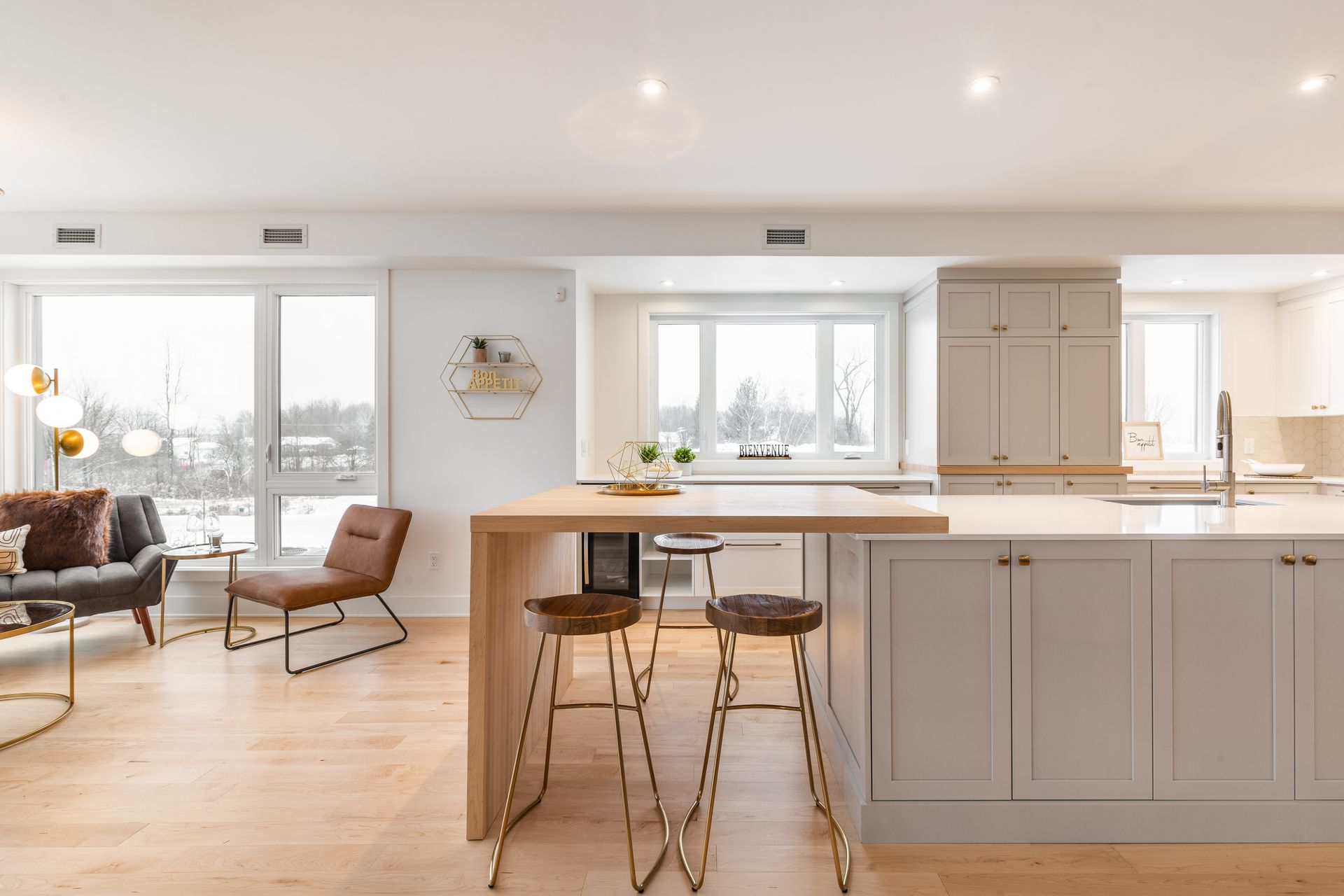 Cuisine et salon modernes et lumineux à aire ouverte avec îlot central, tabourets de bar, parquet clair et grandes fenêtres
