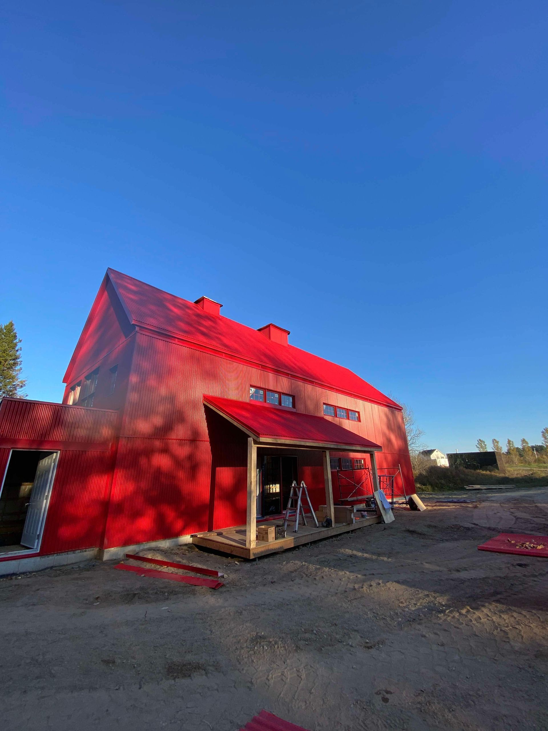 Red barn-style building with bright red roof and siding under a clear blue sky.