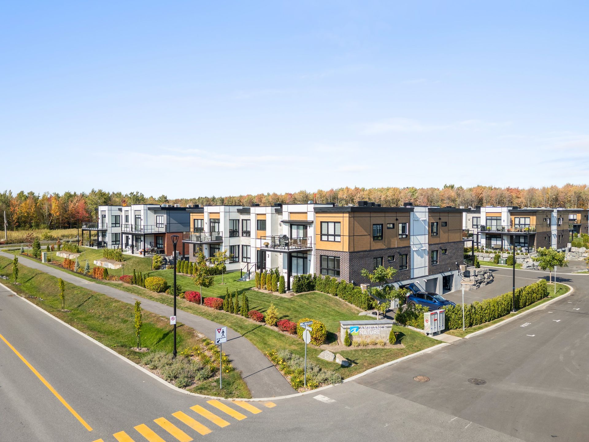 Modern townhouse apartment complex at a street intersection with landscaped yards and autumn trees