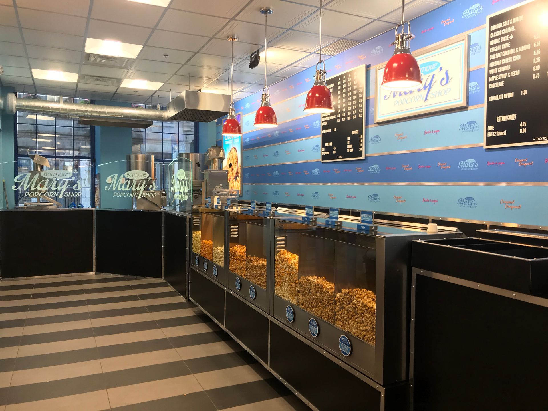 Seafood market interior with glass display cases, red pendant lights, and striped floor tiles.