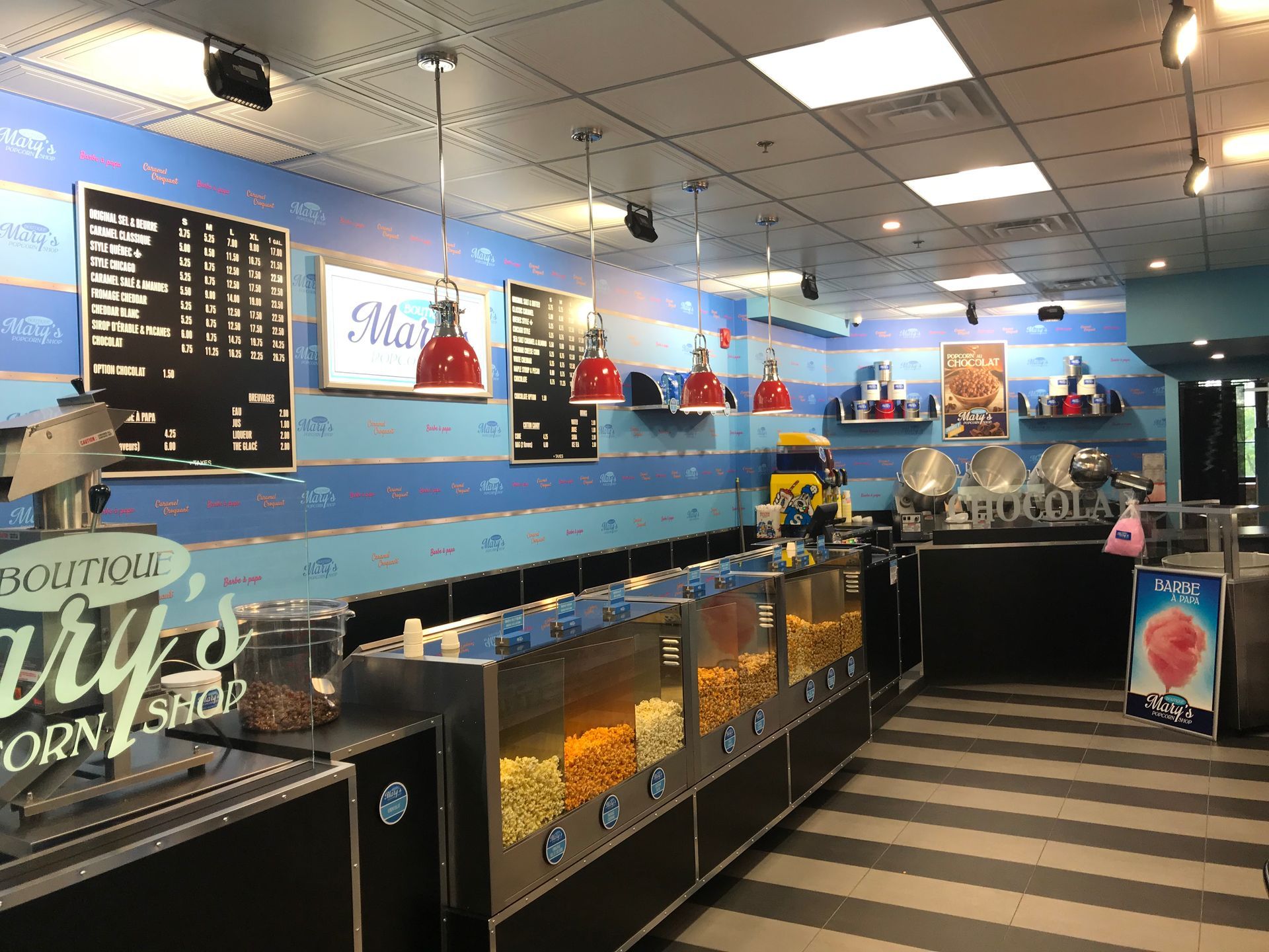 Candy shop interior with glass display cases, blue walls, and striped floor beneath bright ceiling lights