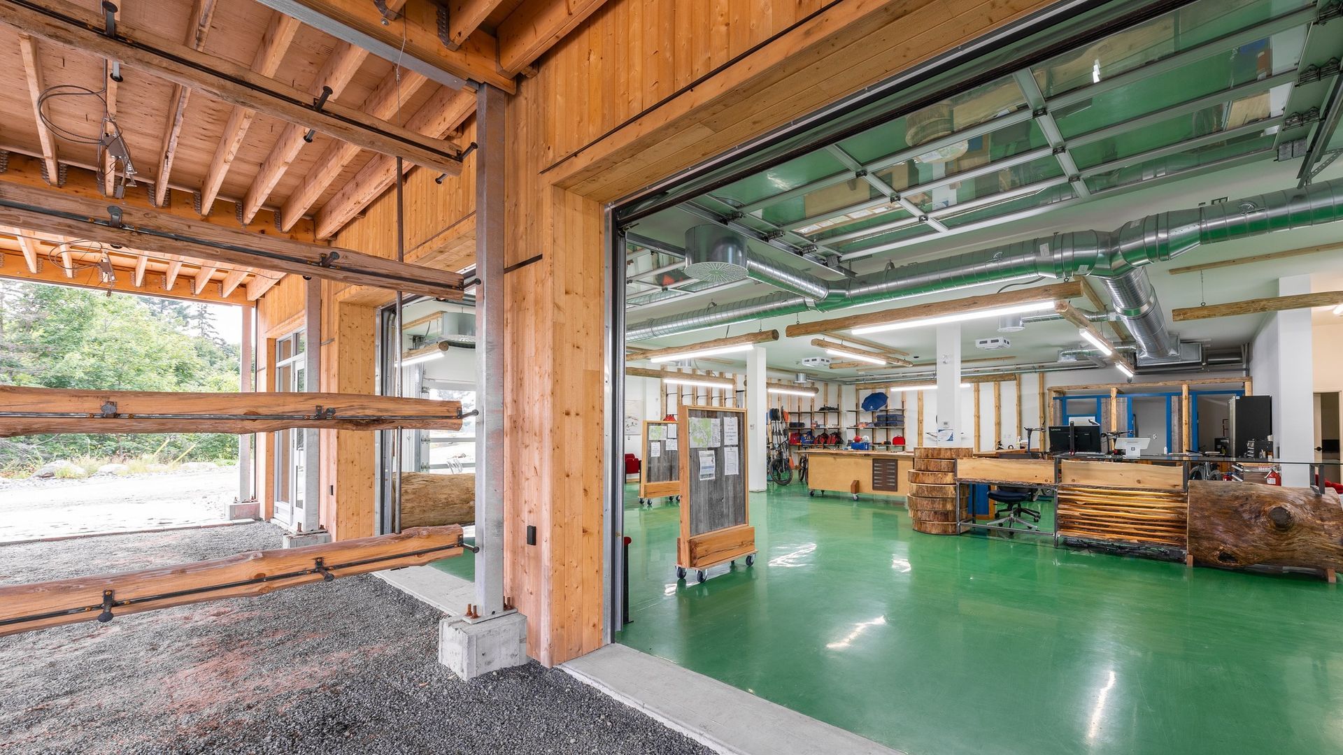 Industrial workshop with green floor, exposed wood beams, and shelves under construction.
