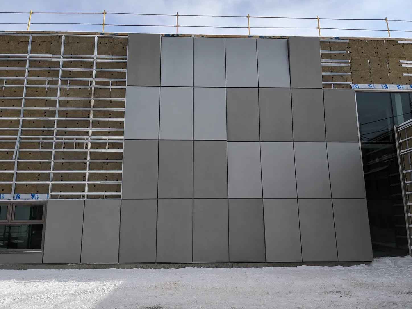 Modern building facade with gray panel cladding and scaffolding on the left