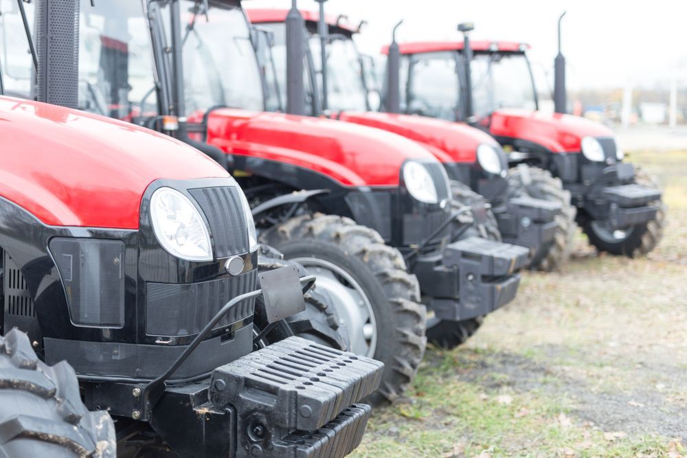 A row of red and black tractors parked in a field — Signature Mechanical In South Gladstone, QLD