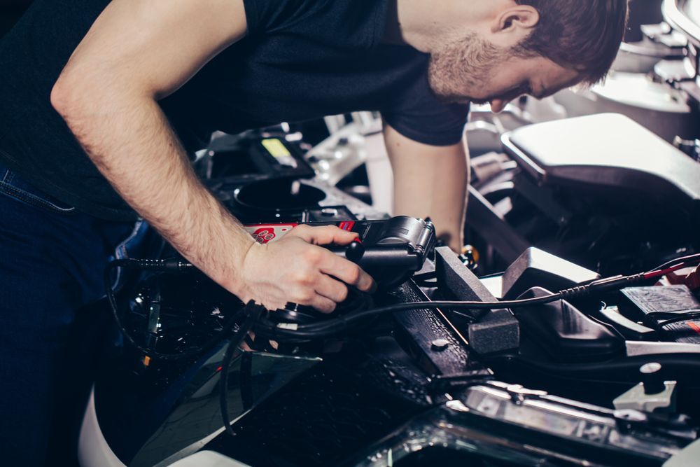 Car Mechanic Inspecting Car Engine Under Hood