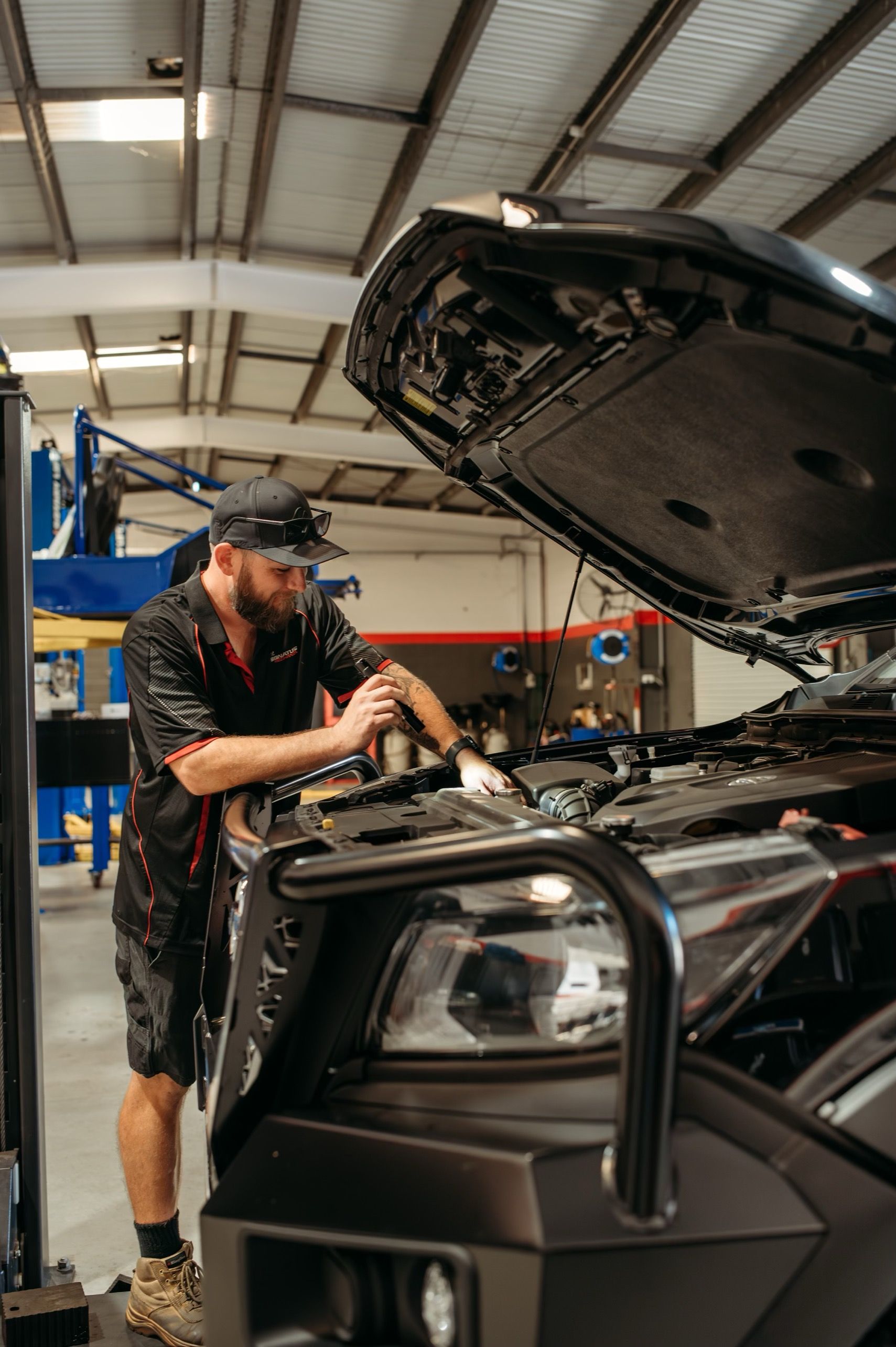A Man Is Working On Engine Of A Car — Signature Mechanical In South Gladstone, QLD