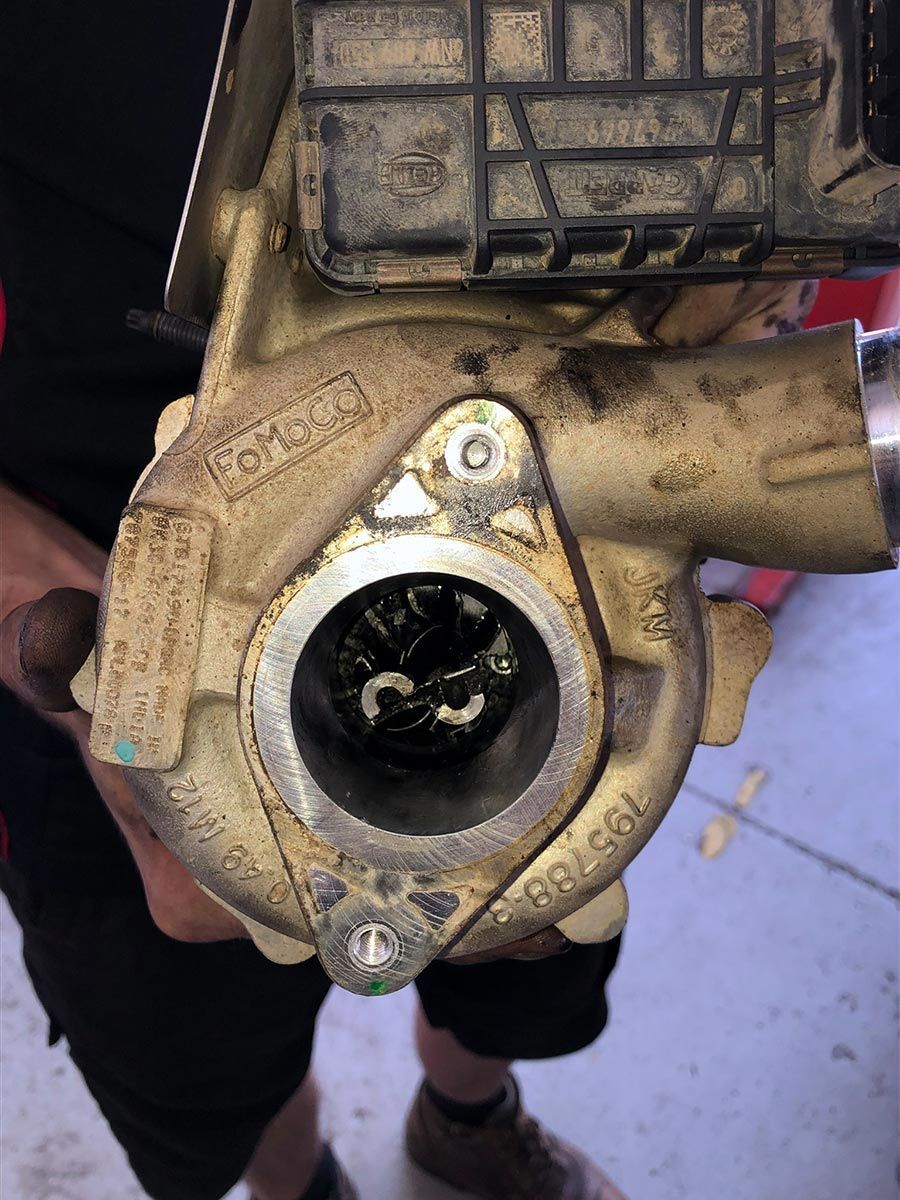 A Person Is Holding A Dirty Turbocharger In Their Hands — Signature Mechanical In South Gladstone, QLD