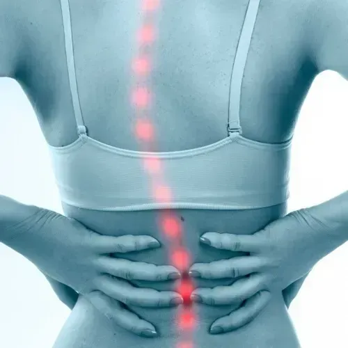 Back of person holding lower back, with glowing red spine highlighting pain area
