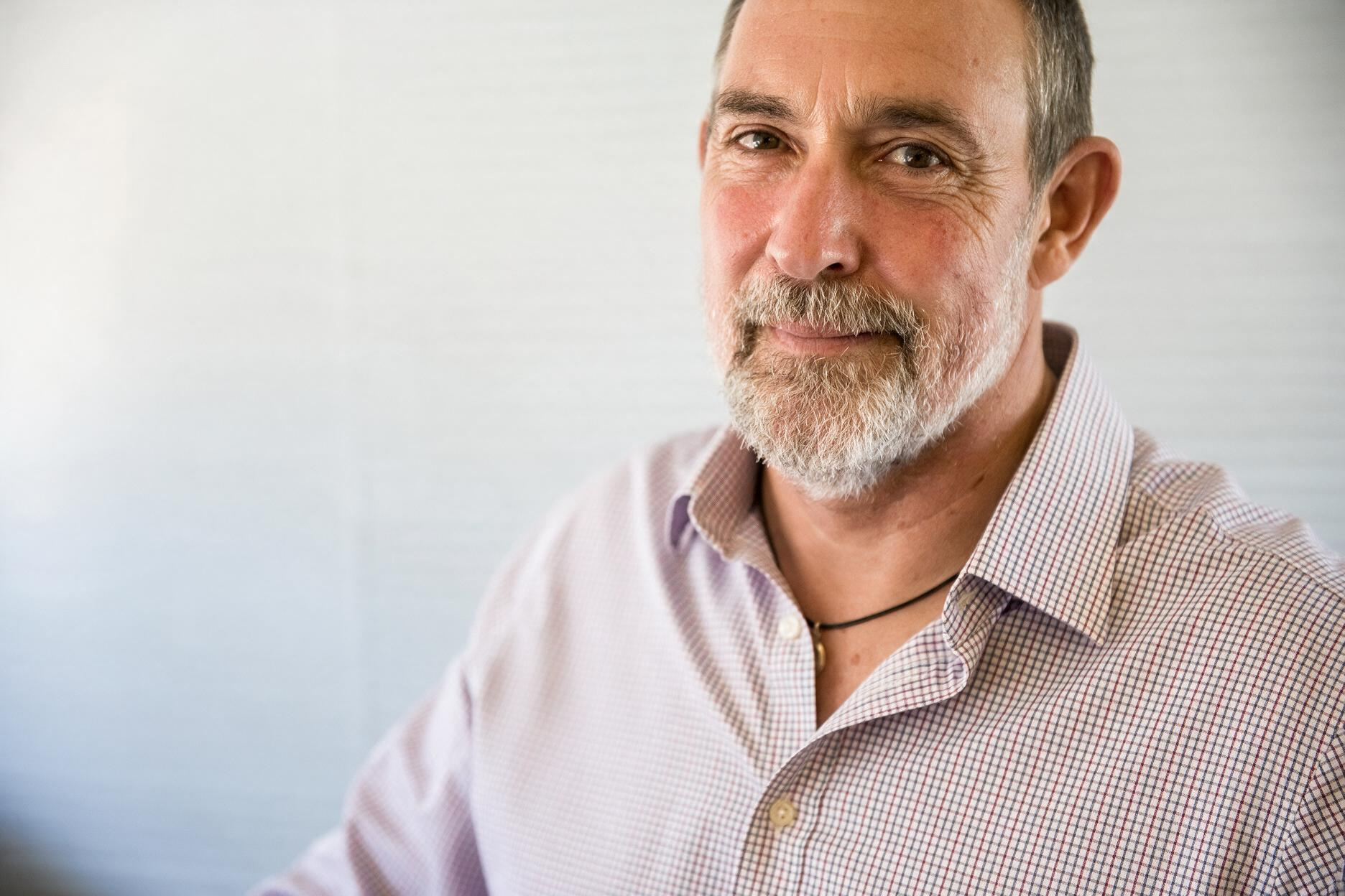 Smiling man in a light checkered shirt against a plain background