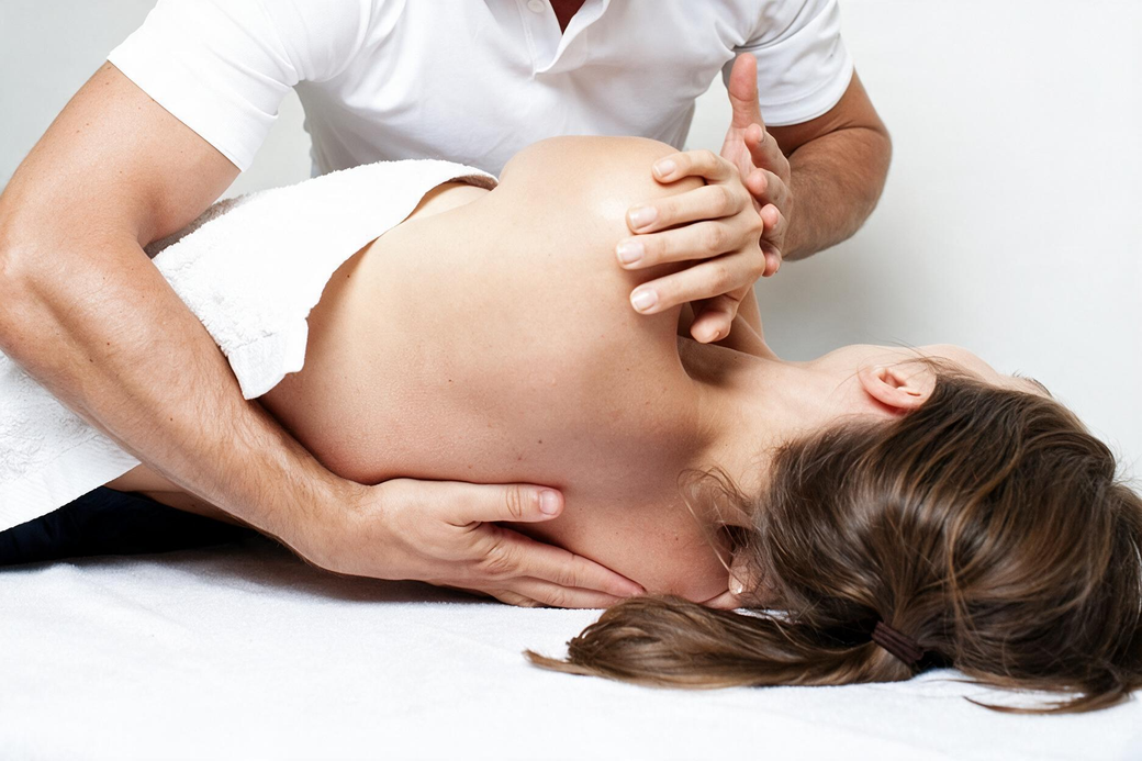Physical therapist performing a back adjustment on a patient lying on a treatment table
