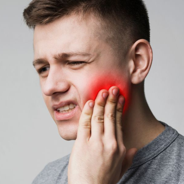 Man holding his cheek with a red glow, showing jaw pain on a gray background