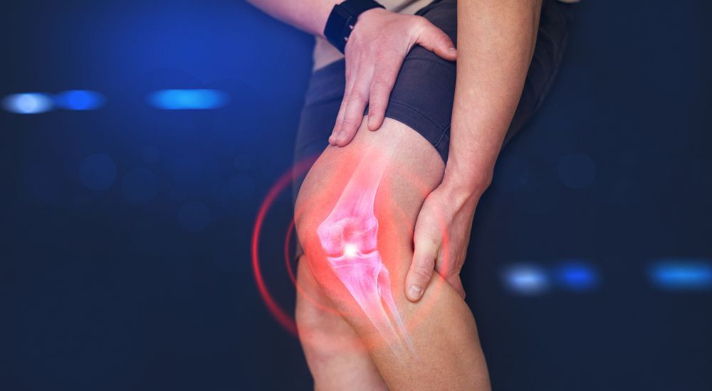 Person holding a glowing red knee, suggesting joint pain or injury.