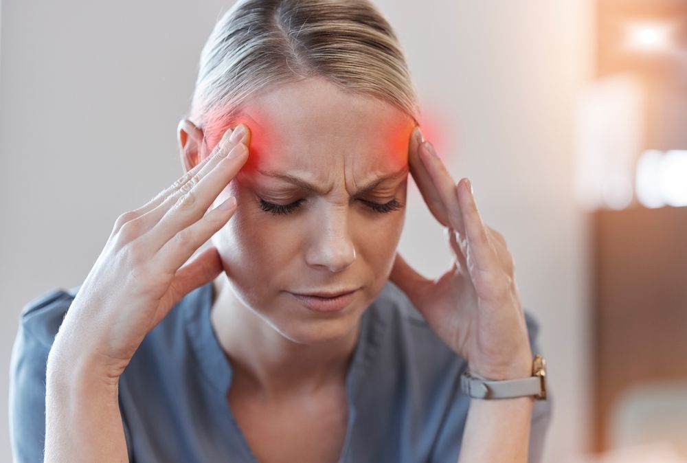 Person holding temples with a pained expression, red glow near forehead, suggesting headache or migraine