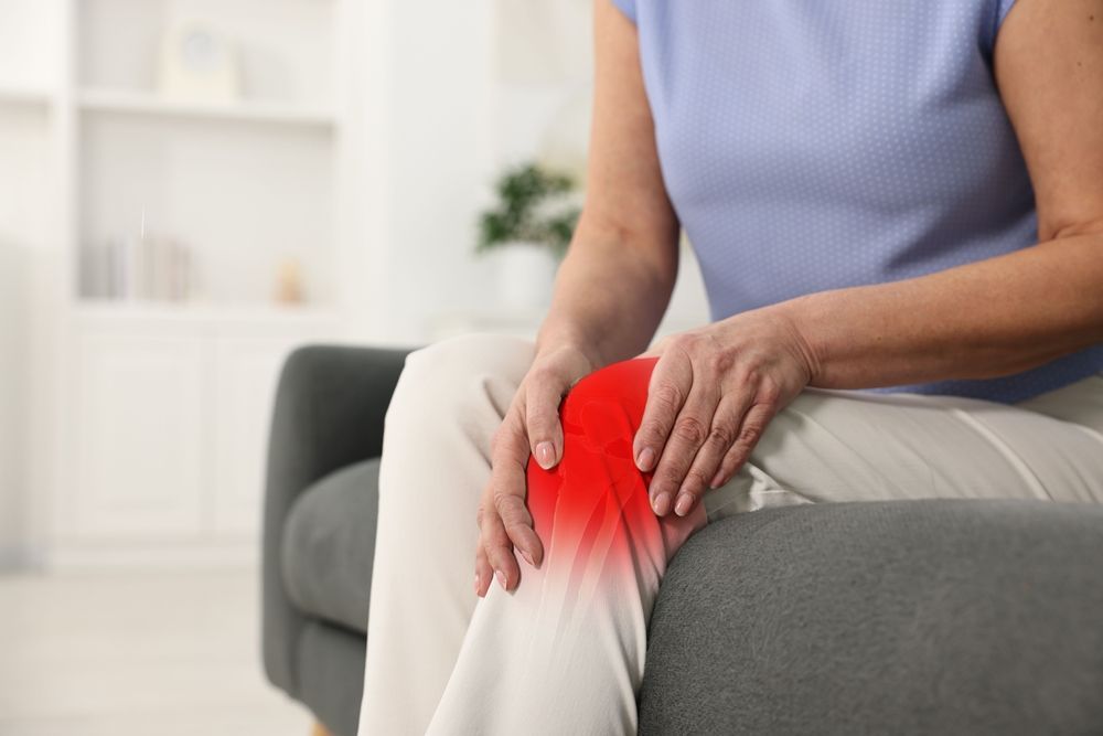 Person holding a glowing red knee while sitting on a couch