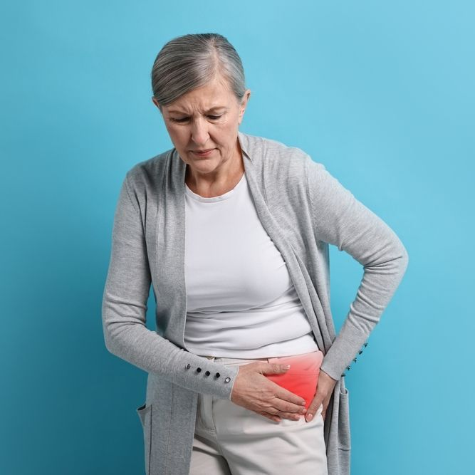 Woman clutching her lower abdomen in pain against a blue background