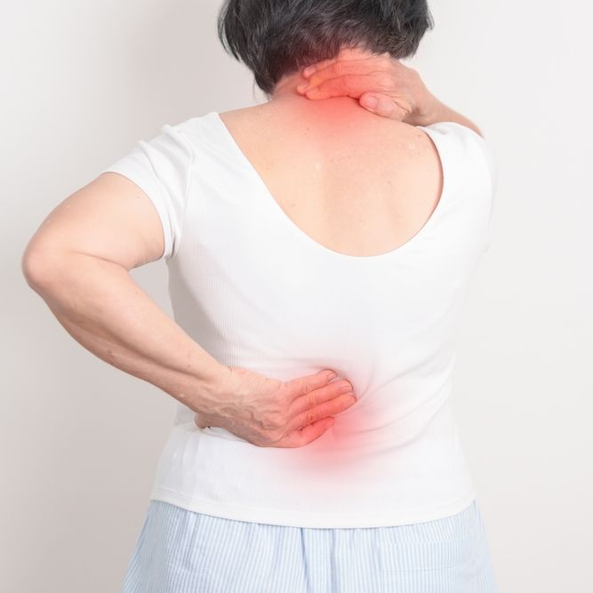 Person holding neck and lower back, indicating pain, with red highlighted areas on a white shirt