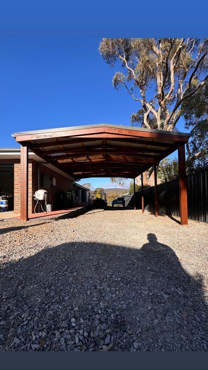 A Carport With a Gravel Driveway. Brown Roof — J&C Quality Construction in Goulburn, NSW