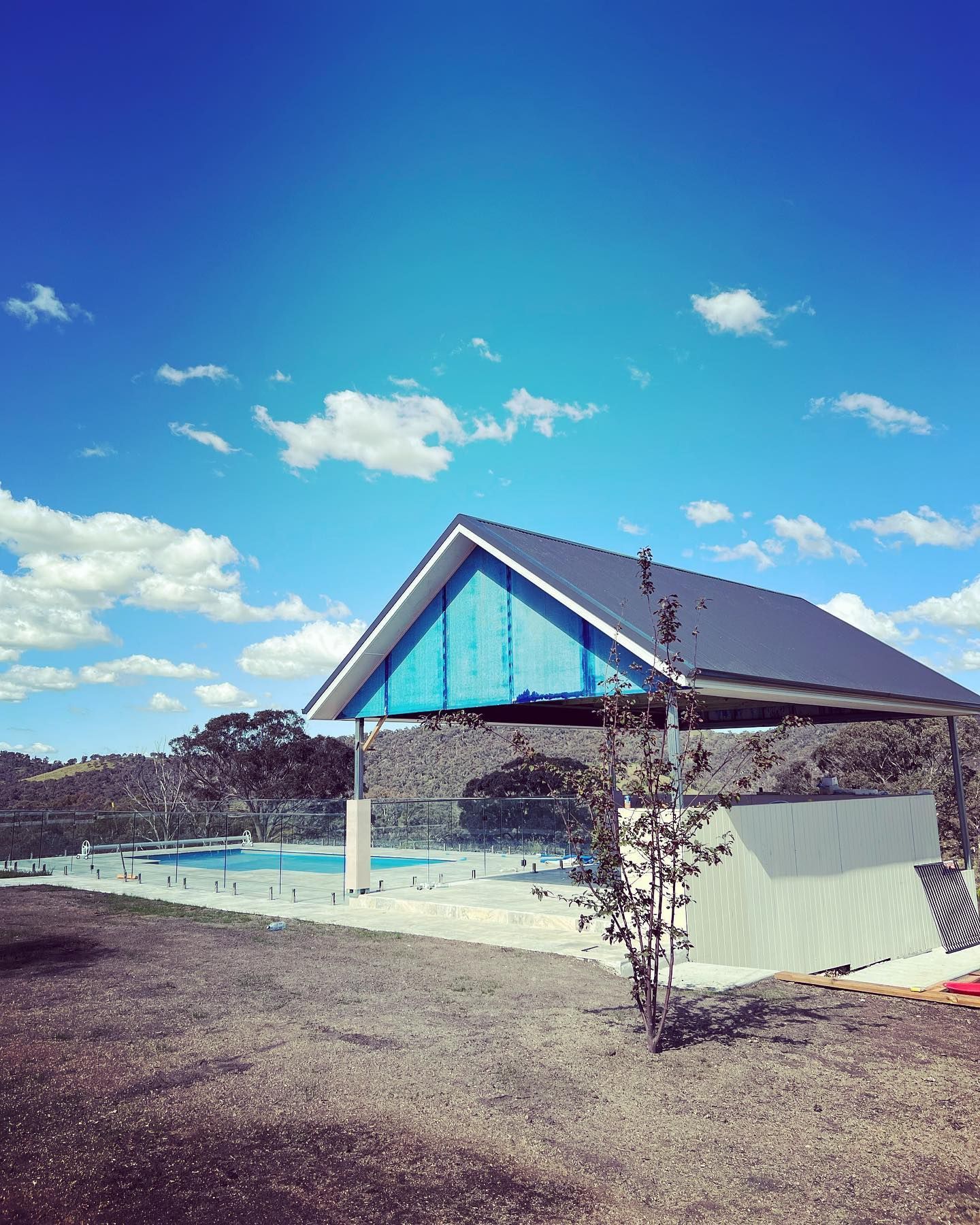 Poolside Shelter With a Blue Roof Against a Vibrant Blue Sky — J&C Quality Construction in Canberra, ACT