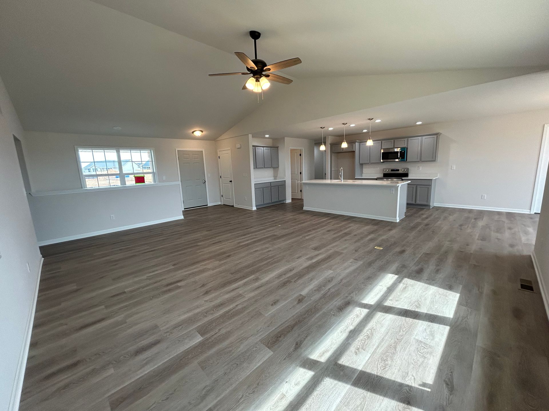 Open-concept living space with grey flooring, kitchen, and high ceiling.