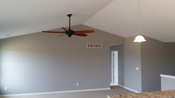 Living room with vaulted ceiling, gray walls, a ceiling fan, and pendant light.