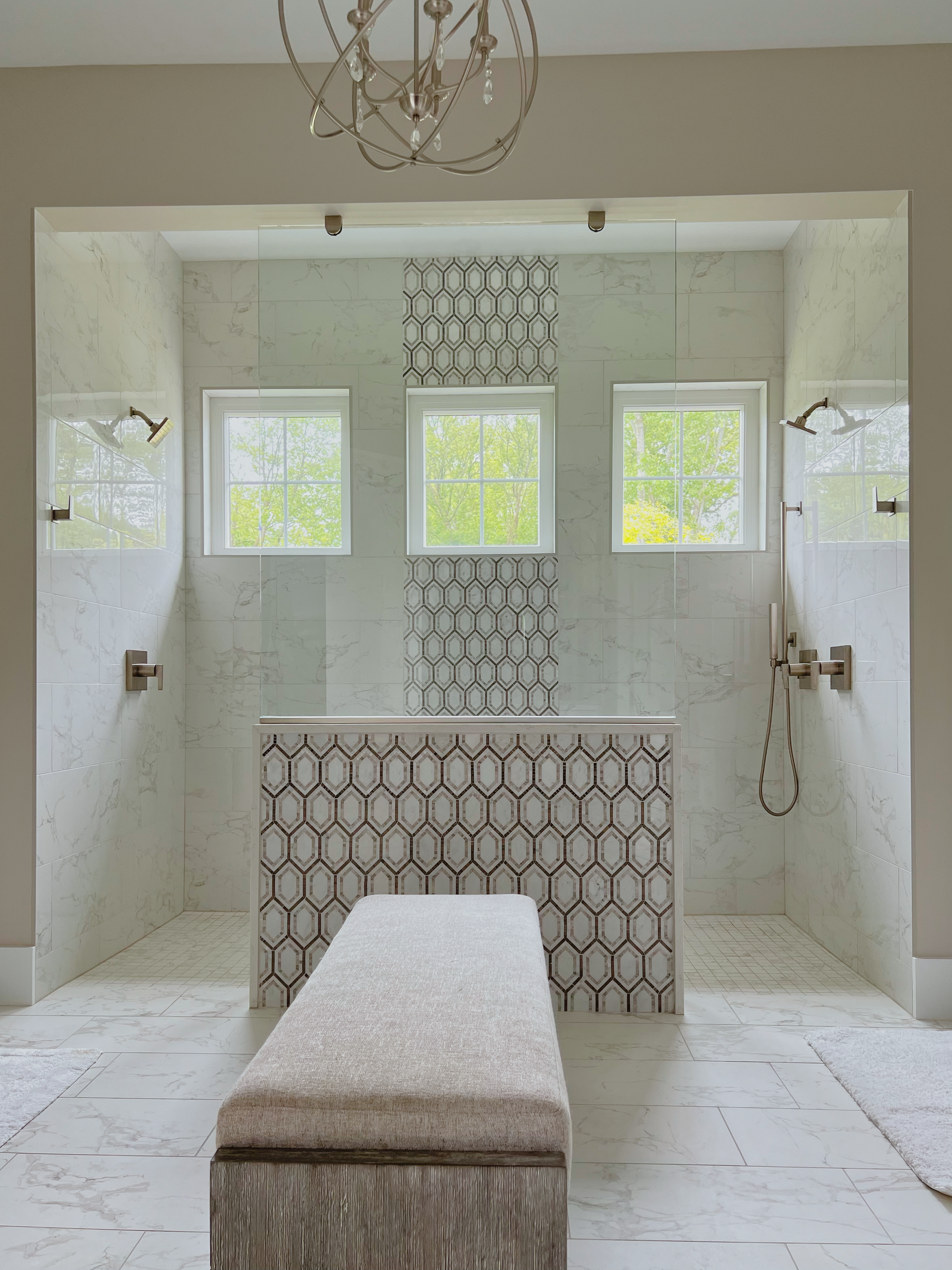 Spacious bathroom with a central shower bench, decorative tile, three windows, and dual shower heads.