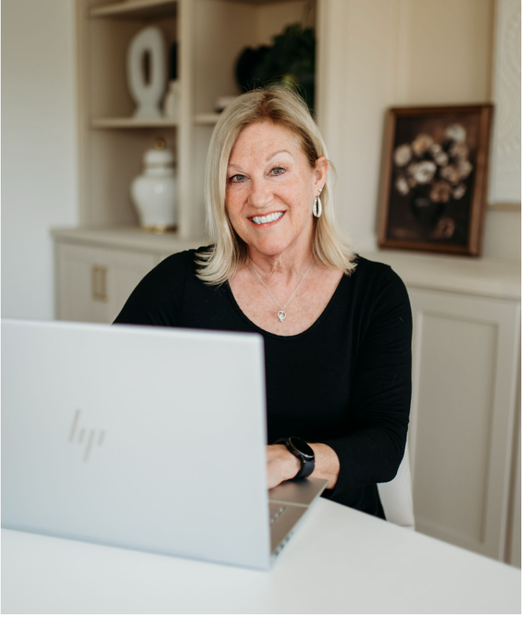 Woman smiling at a desk with a laptop in a bright office setting