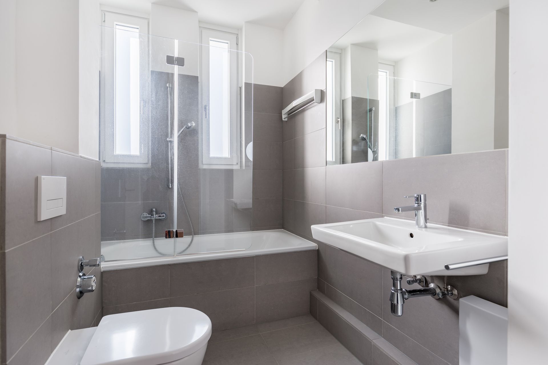 A bathroom with a toilet , sink , bathtub and mirror.