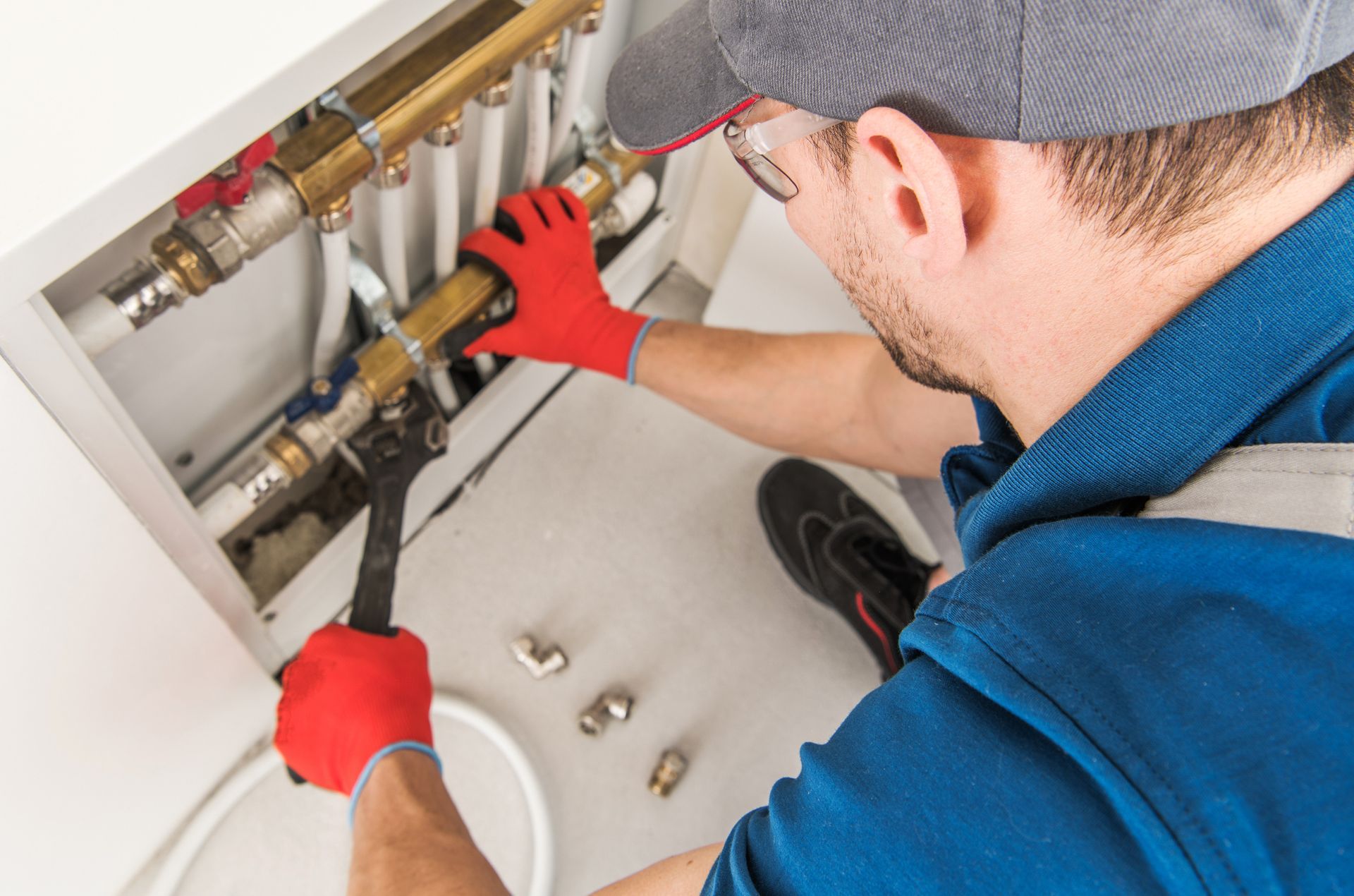 A man is working on a heating system with a wrench.