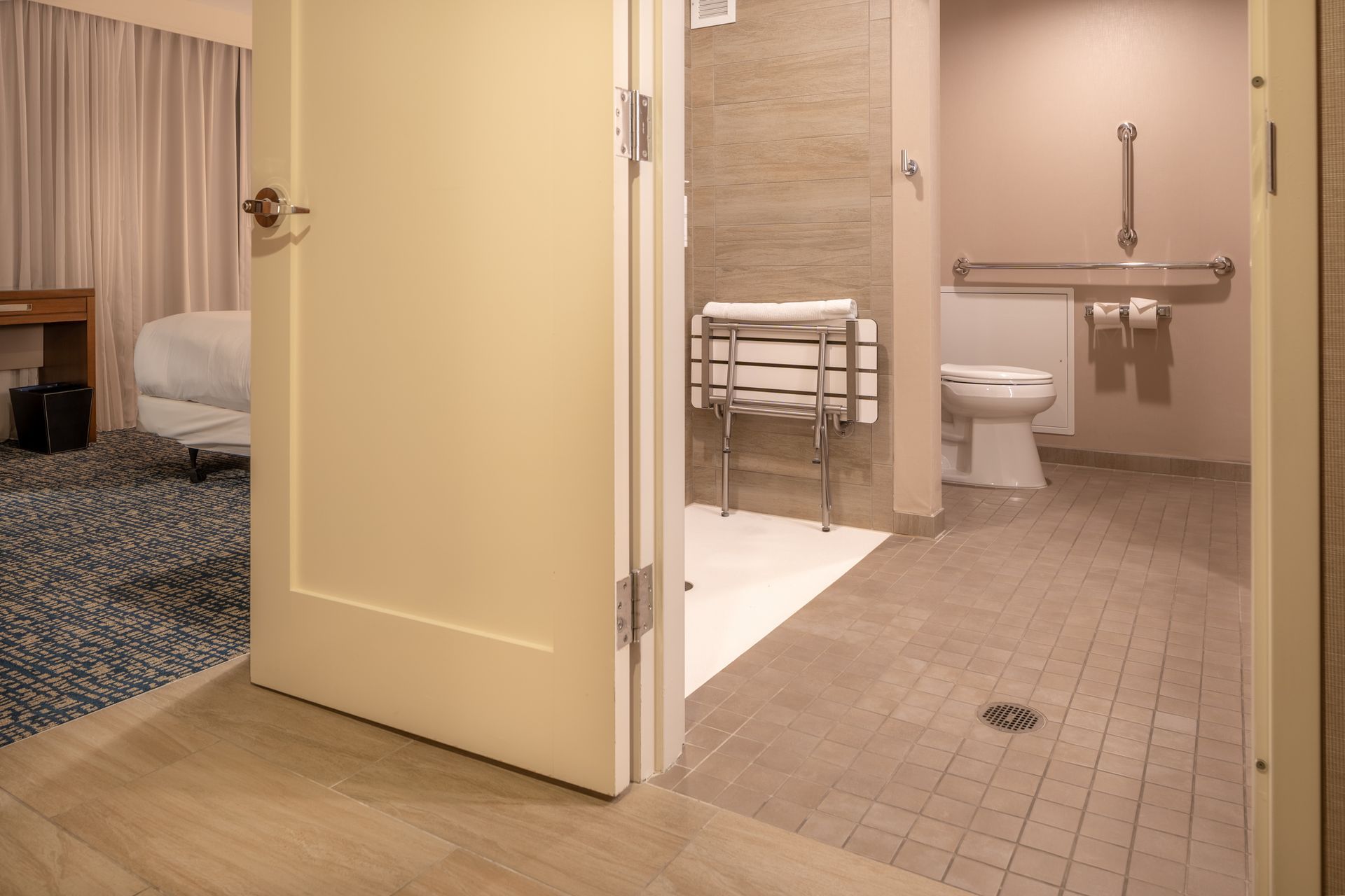A bathroom in a hotel room with a toilet and shower.