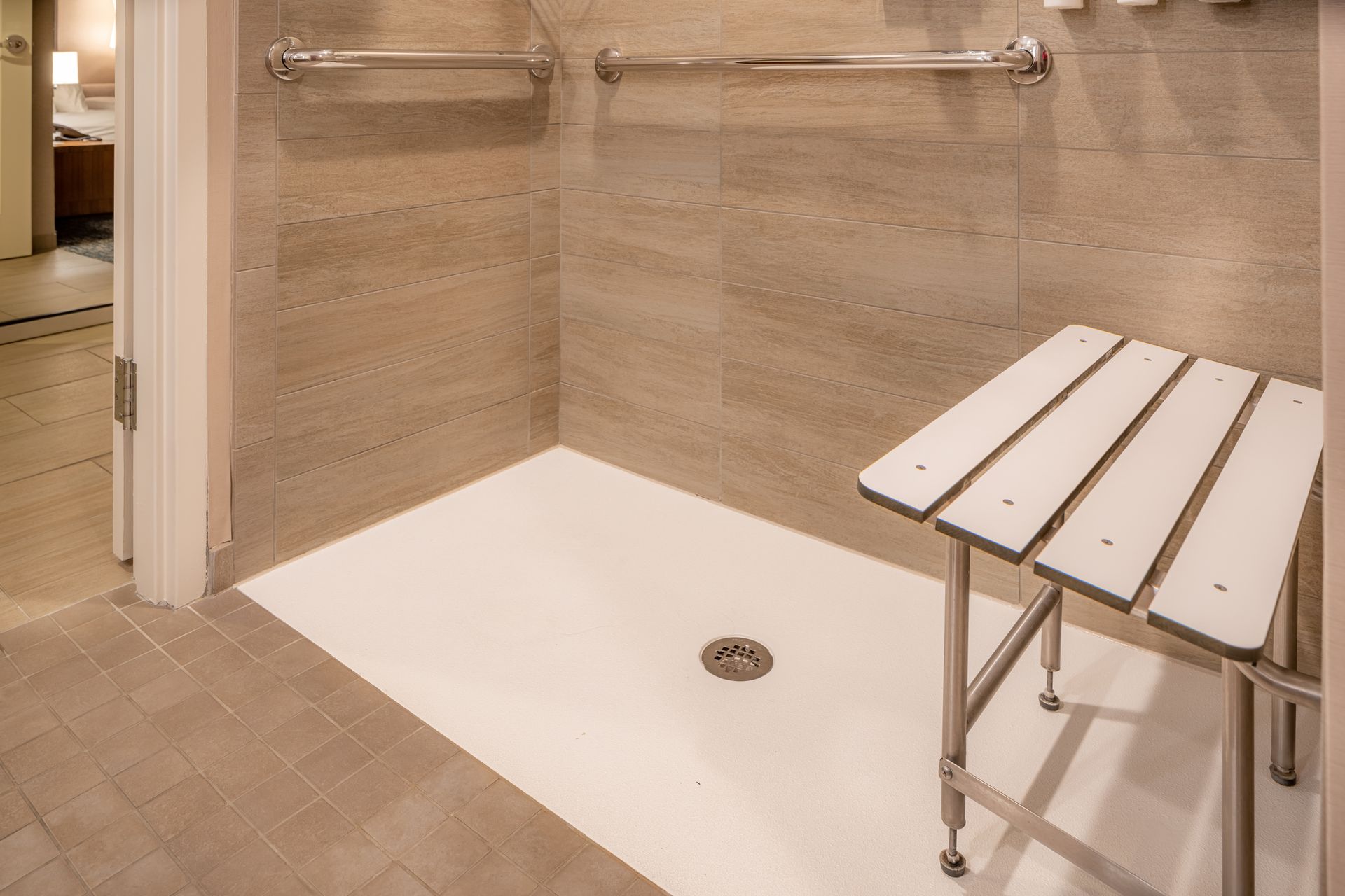 A bathroom with a walk in shower and a bench.
