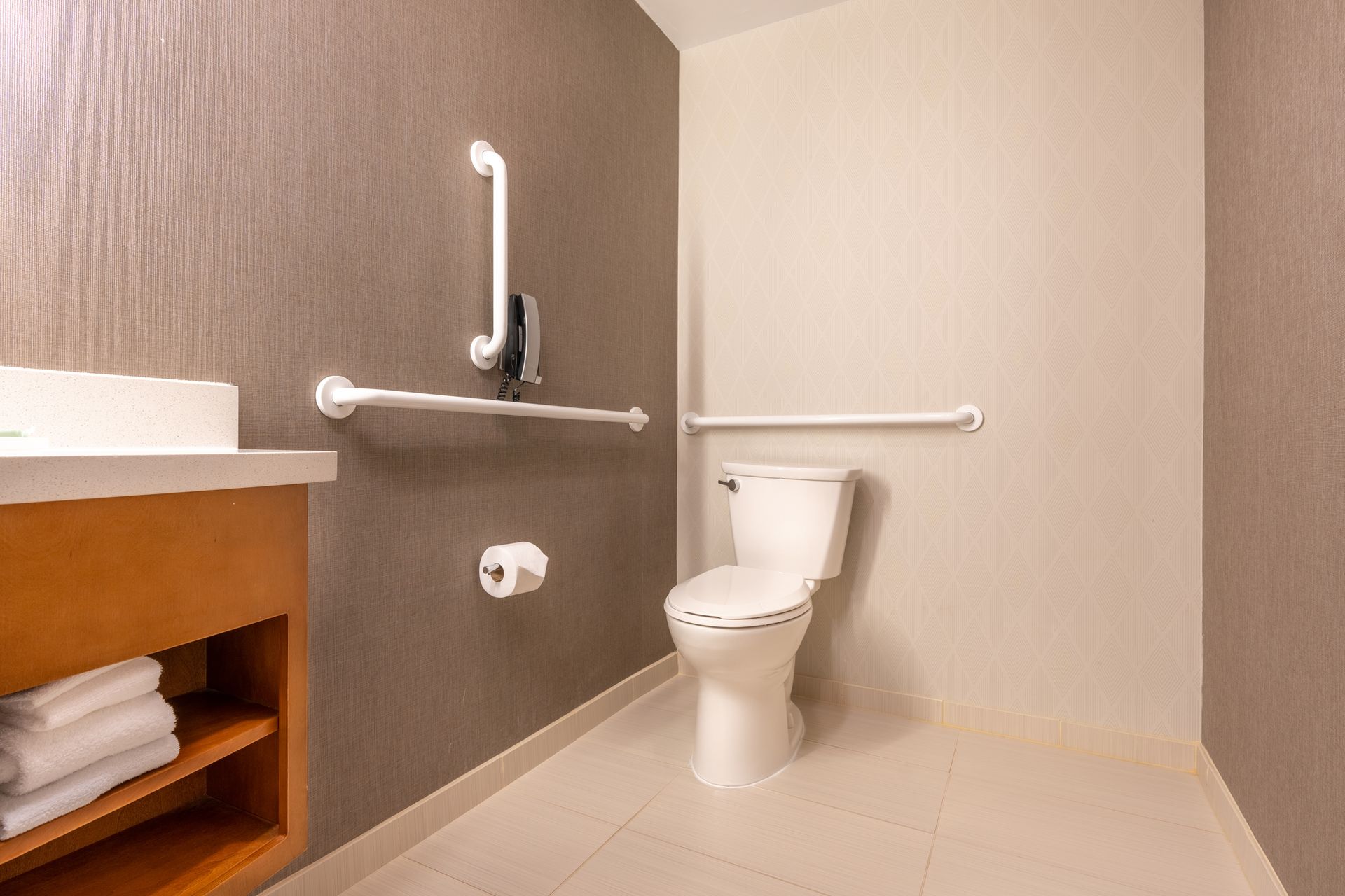 A bathroom with a toilet , sink , and handrails.