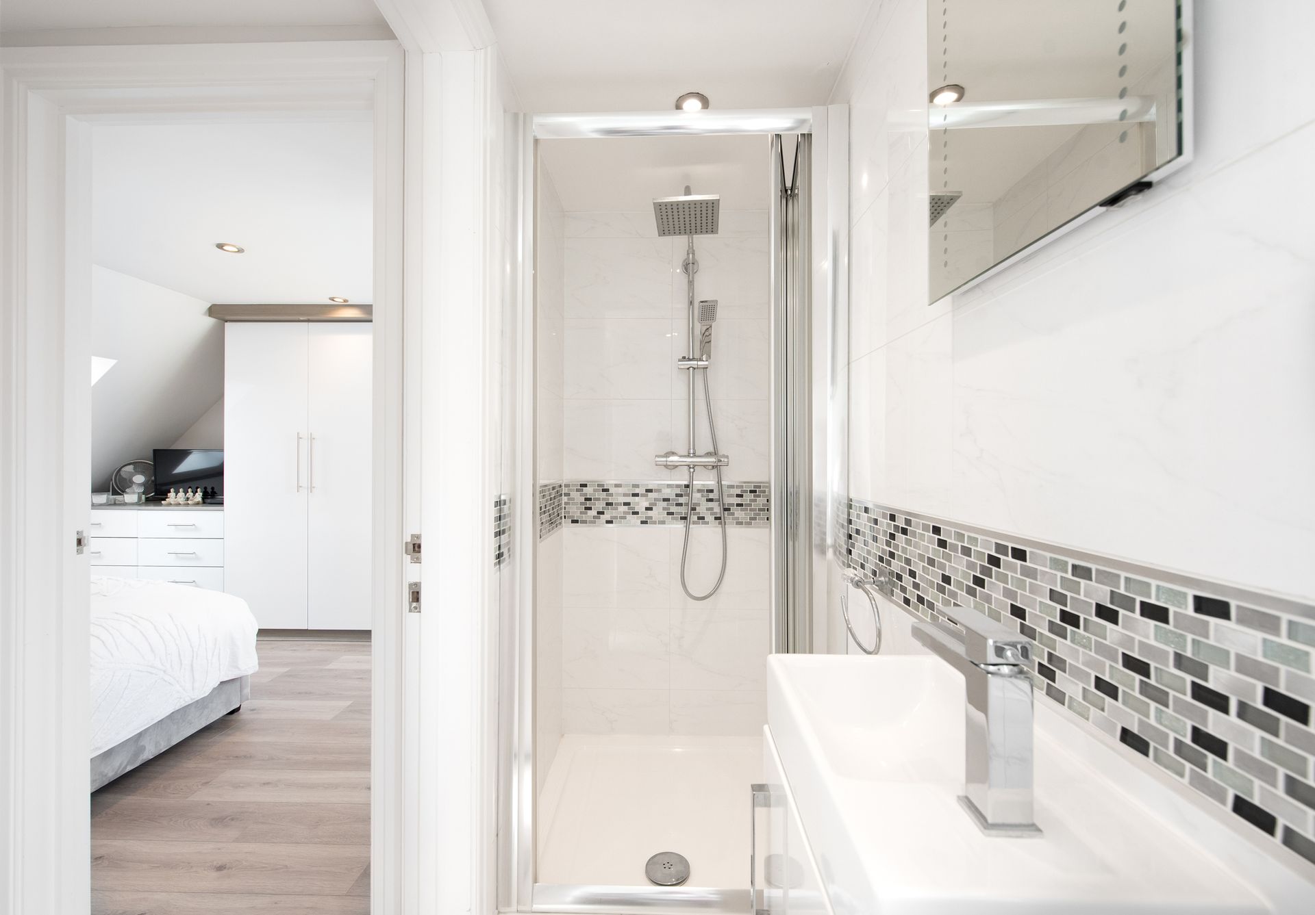 A bathroom with a shower , sink and mirror.