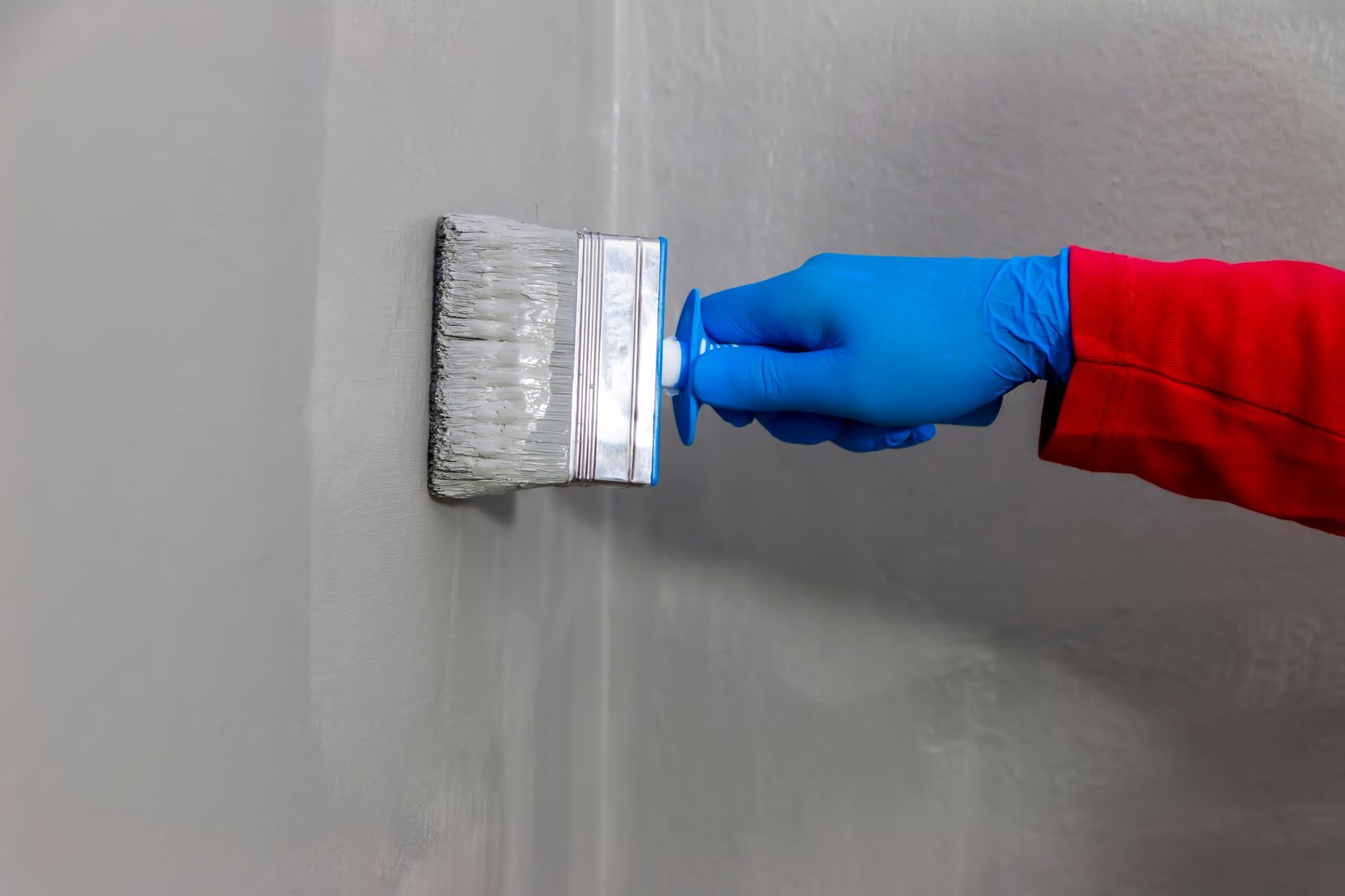 A person is painting a wall with a brush.